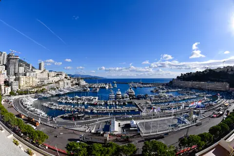 Veduta dall’alto in grandangolo del porto di Monaco con yacht, edifici e circuito, sotto un cielo azzurro