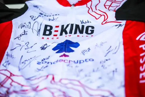 Dettaglio di una maglia bianca e rossa BEKING Back to Bike coperta di firme nere