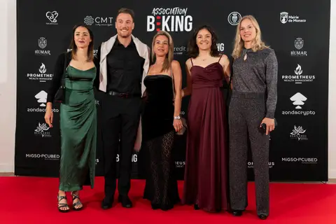 Cinque ospiti in abiti eleganti posano sul tappeto rosso davanti al fondale Association BEKING