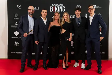 Sei ospiti in abiti eleganti posano insieme sul tappeto rosso davanti al fondale Association BEKING